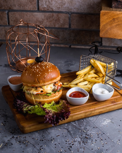 Foto gratuita hamburguesa con queso con papas fritas en la mesa