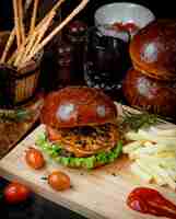 Foto gratuita hamburguesa con queso y papas fritas en una tabla de madera