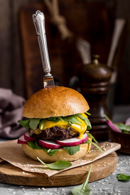 Hamburguesa con queso vista frontal en la tabla de cortar con cuchillo