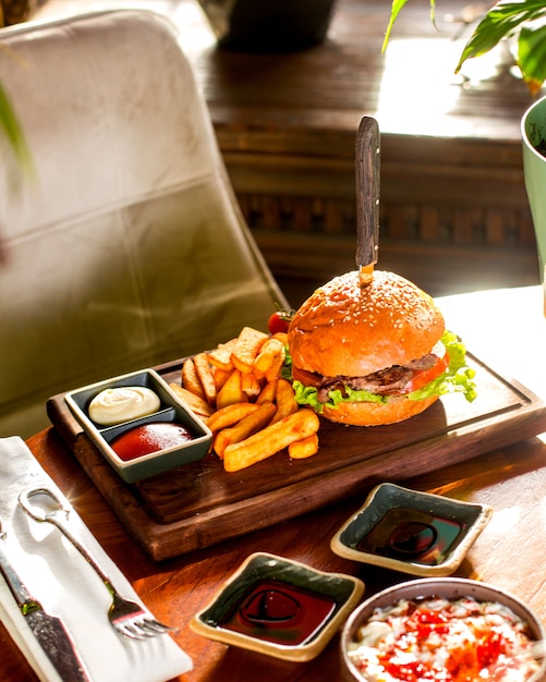 Hamburguesa servida con papas fritas, salsa de tomate y mayonesa