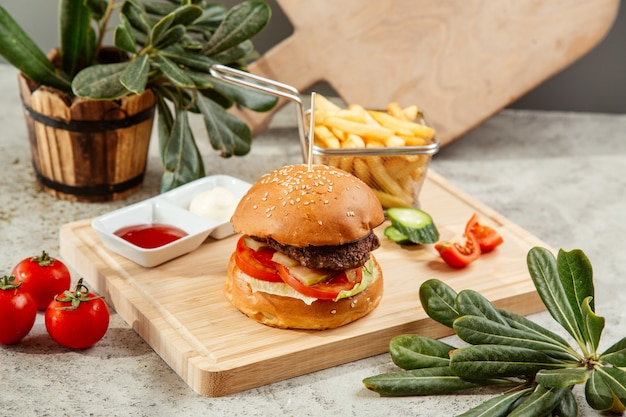 Hamburguesa servida con papas fritas y salsa de tomate