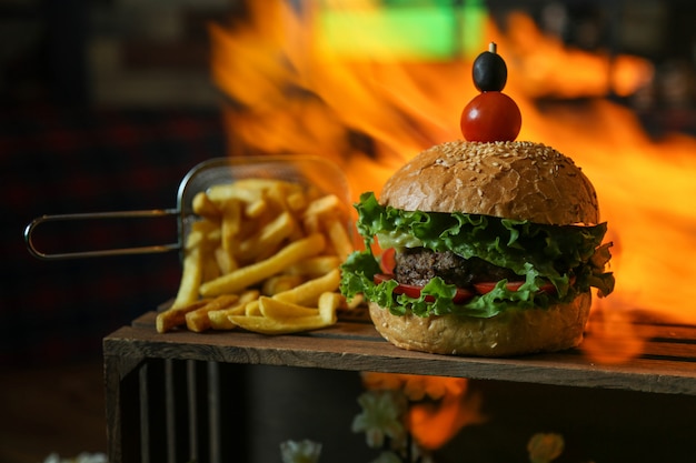 Hamburguesa de ternera lechuga tomate pepino aceitunas papas fritas vista lateral