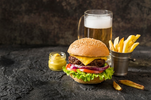 Hamburguesa de ternera vista frontal, papas fritas y salsa con cerveza