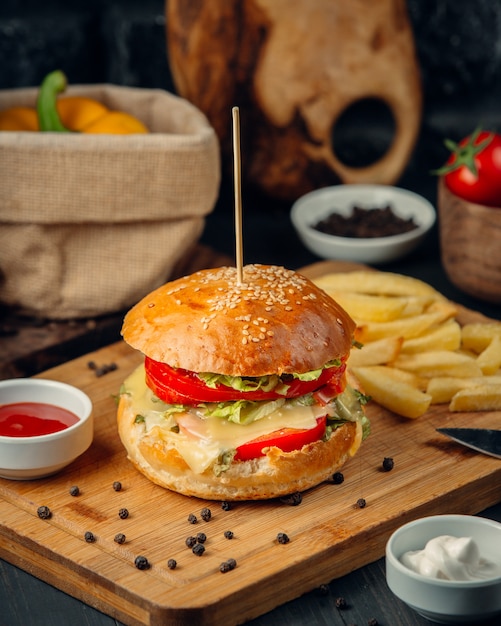 Hamburguesa con tomate, lechuga, queso derretido y papas fritas, ketcup, cerrar