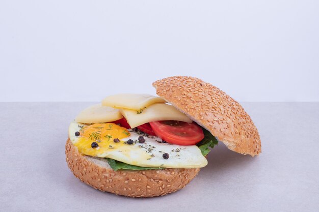 Hamburguesa con tortilla, tomate, champiñones y cebolla en blanco.