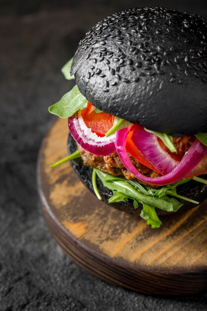 Hamburguesa vegetariana de alto ángulo con bollos negros sobre tabla de cortar