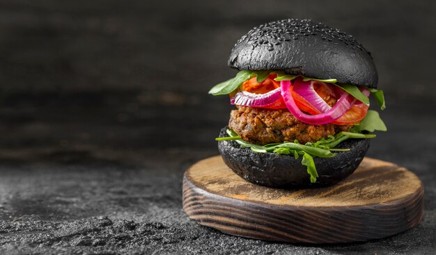 Hamburguesa vegetariana vista frontal con bollos negros en la tabla de cortar