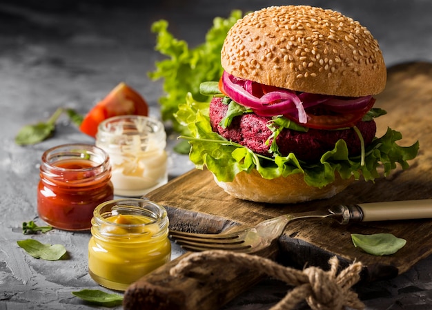 Hamburguesa vegetariana vista frontal en tabla de cortar con salsas