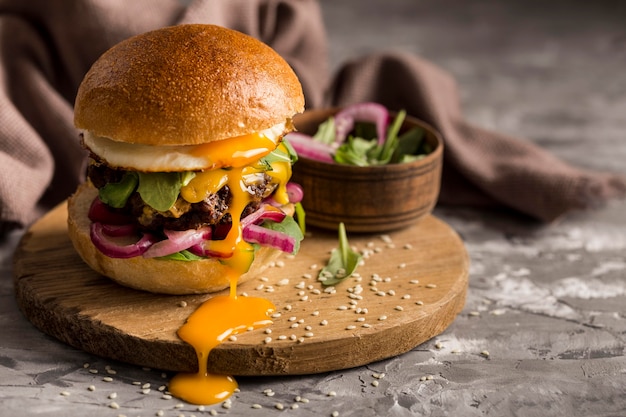 Hamburguesa de vista frontal con huevo frito en tabla de cortar