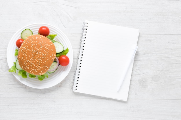 Foto gratuita hamburguesa de vista superior para veganos junto al cuaderno vacío