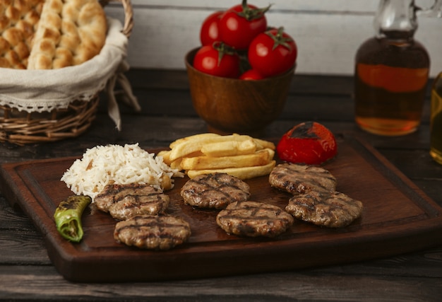 hamburguesas de carne de res servidas con papas fritas, arroz y verduras a la parrilla