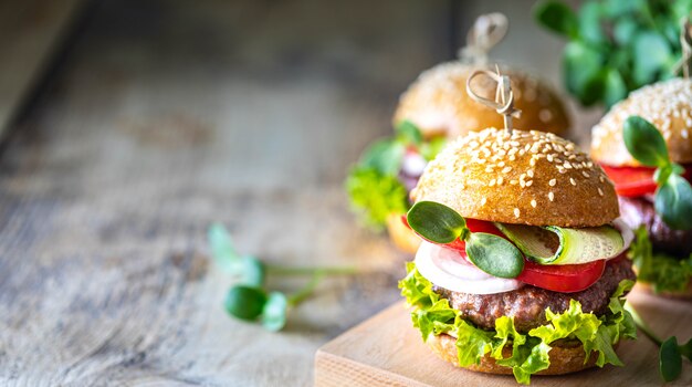 Hamburguesas caseras con chuleta, lechuga fresca, tomates, cebollas en una mesa de madera. copia espacio