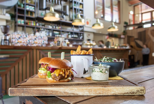 Foto gratuita hamburguesas con papas fritas en una taza y salsa en una bandeja de madera