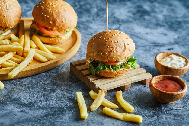 Hamburguesas con patatas fritas en la plancha de madera