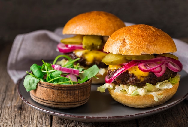 Foto gratuita hamburguesas de ternera vista frontal con encurtidos en tabla de cortar