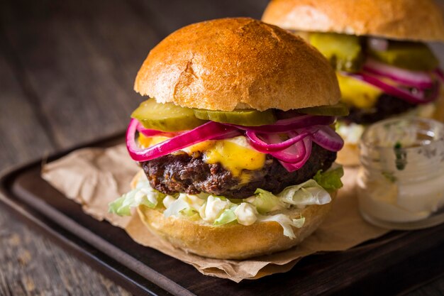 Hamburguesas de vista frontal con pepinillos en tabla de cortar