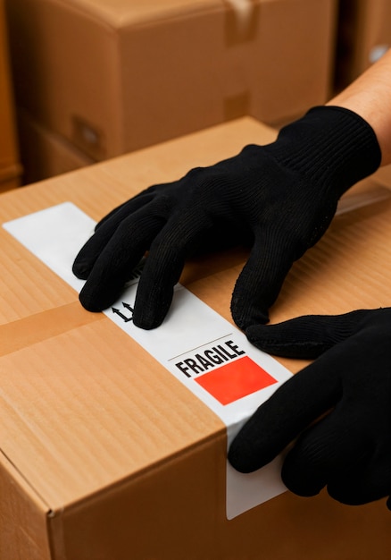 Hands with black gloves placing a fragile sticker