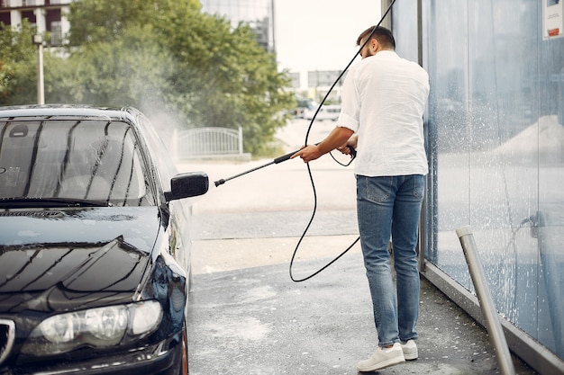 Foto gratuita handsomen hombre en una camisa blanca lavando su auto