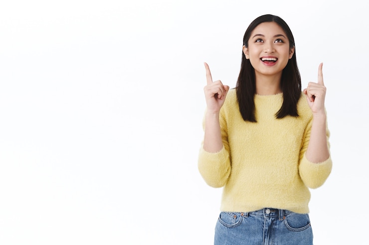 Photo Gratis happy satisfied cute dreamy asian girl seeing something beautiful, found exactly what need in store, pointing and looking up with amazed cheerful smile, feeling relieved or delighted