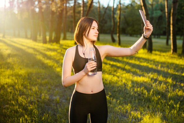 Happy young sportsgirl hace selfie retrato en smartphone.