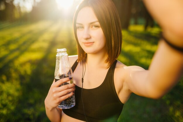 Happy young sportsgirl hace selfie retrato en smartphone.