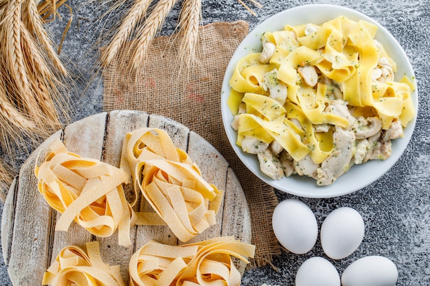 Harina de pasta con huevos, cereales, pasta cruda, tabla de madera en un plato