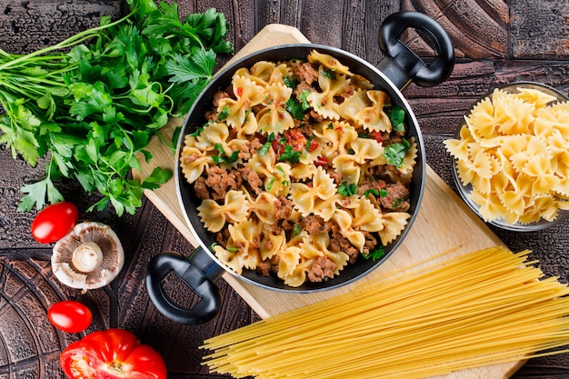 Harina de pasta en sartén con pasta cruda, champiñones, perejil, tomate