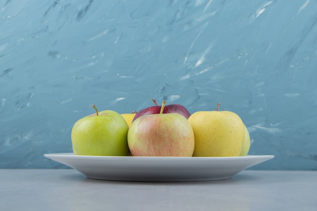 Hay un montón de manzanas frescas en un plato blanco.