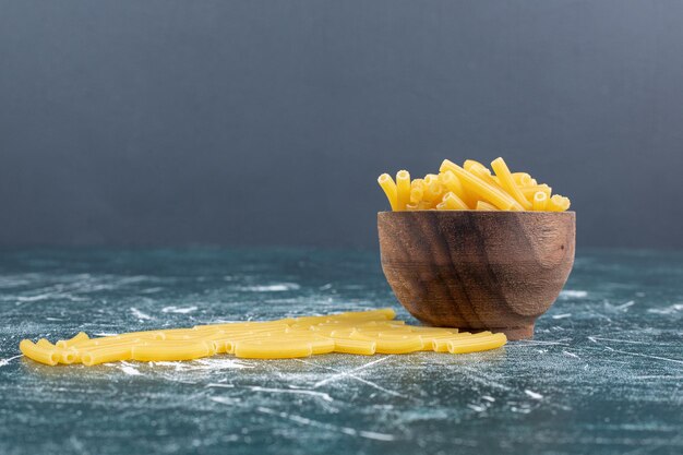 Hay un montón de pasta cruda en un tazón de madera.