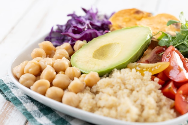 Foto gratuita healthy salad with avocadolettucetomato and chickpeas on white wooden table