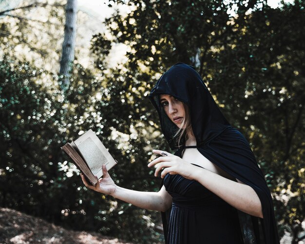 Hechicera con libro de hechizos en un bosque soleado