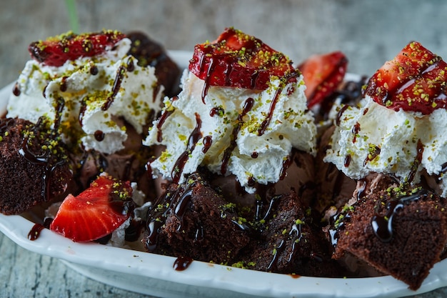 Helado de chocolate negro con fresa en la placa blanca.