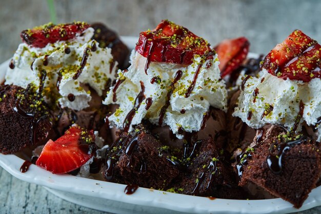 Helado de chocolate negro con fresa en la placa blanca.