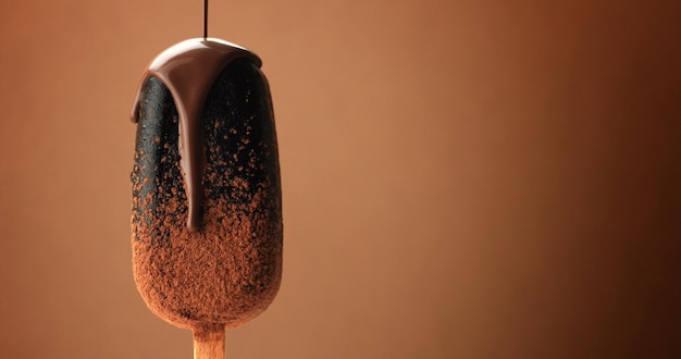 Helado de chocolate en un palo y chocolate líquido lo cubrió Diferentes texturas de chocolate sobre fondo marrón