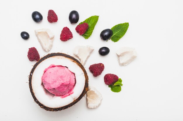 Helado congelado en el interior del coco con frambuesa; Menta y uvas sobre fondo blanco