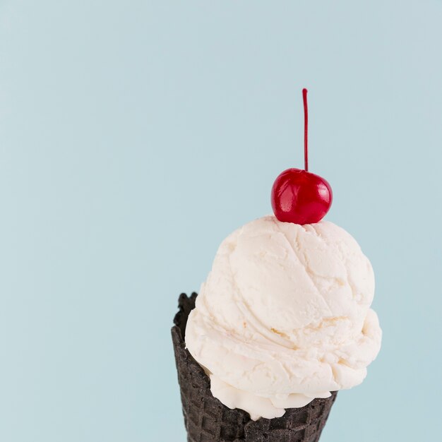 Helado en cono negro con cereza arriba.