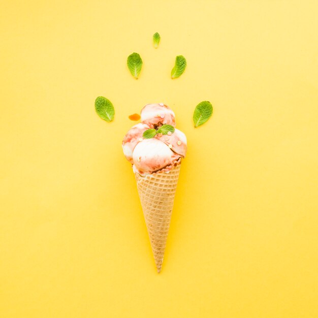 Helado en cono de waffle con sirope y menta.