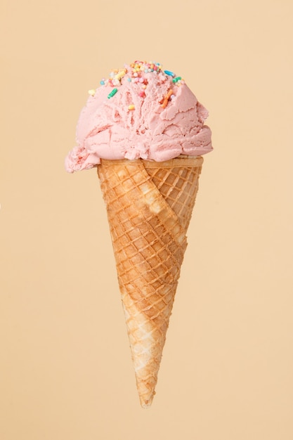 Helado de corneta con una bola de fresa sobre una superficie colorida