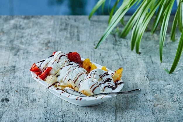 Foto gratuita helado de fresa, plátano, naranja en el plato blanco con cuchara