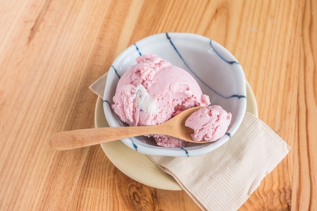 Helado de fresa en un tazón en la mesa de madera.