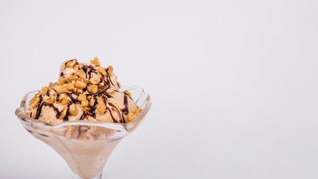 Helado con nueces y cobertura en un recipiente de vidrio.