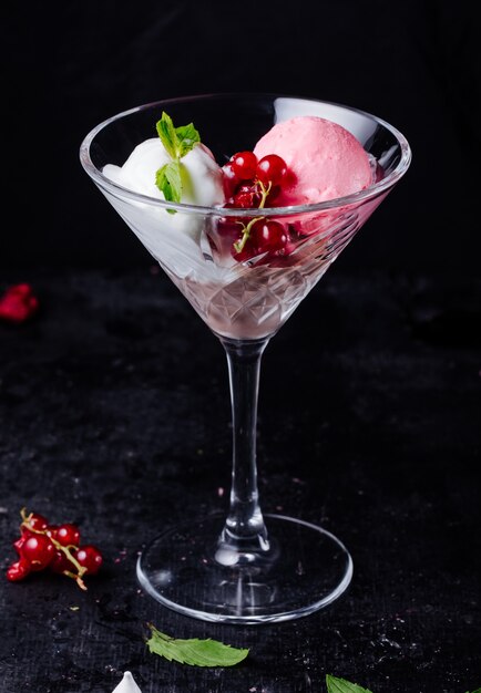 Helado de vainilla y fresa con bayas, hojas de menta y cubitos de hielo.