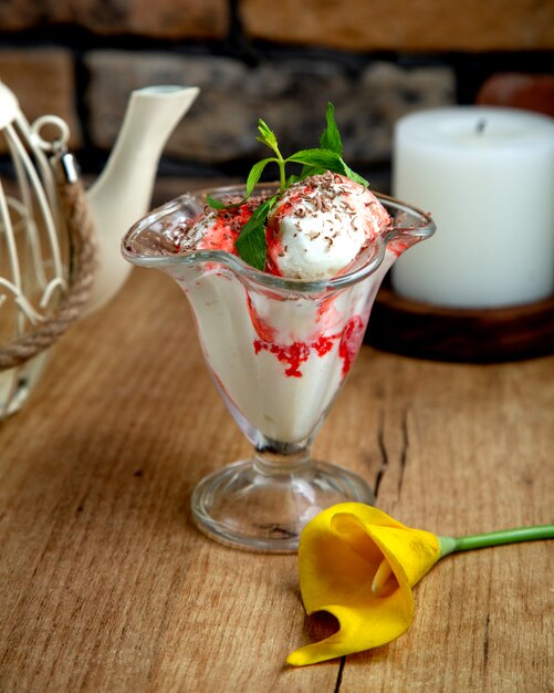 Helado de vainilla con jarabe de fresa adornado con chocolate rallado