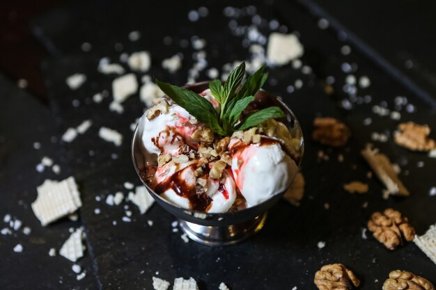 Helado de vainilla con nueces fresa syrop vista lateral de menta