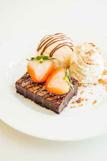 Helado de vainilla con pastel de brownie de chocolate con fresa en la parte superior