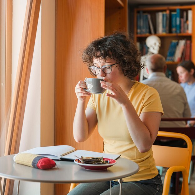 Hembra adolescente bebiendo bebida mientras estudiaba