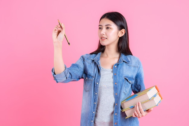 Hembra adolescente sosteniendo libros en brazos y usar lápiz