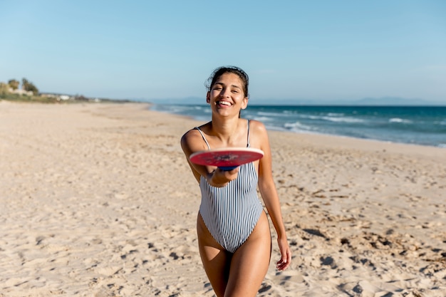 Hembra adulta feliz que señala en la cámara con la raqueta de tenis