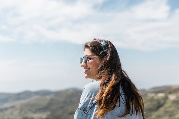 Hembra adulta sonriente en montañas soleadas