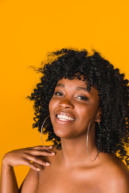 Hembra afroamericana joven sonriente en fondo coloreado